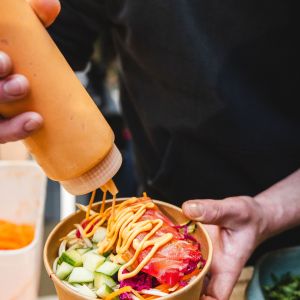 Sauce being added to a poke bowl